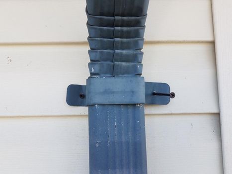 blue metal gutter downspout pipe and white home siding