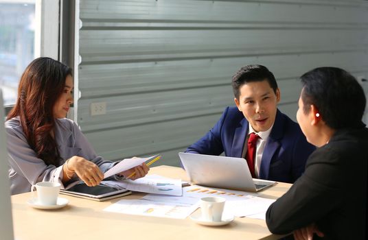 young business team working together at office. Manager pointing at a chart and explaining the analysis about business strategies. Top view shot of business hand shake