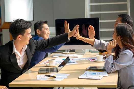 young business team working together at office. Manager pointing at a chart and explaining the analysis about business strategies. Top view shot of business hand shake