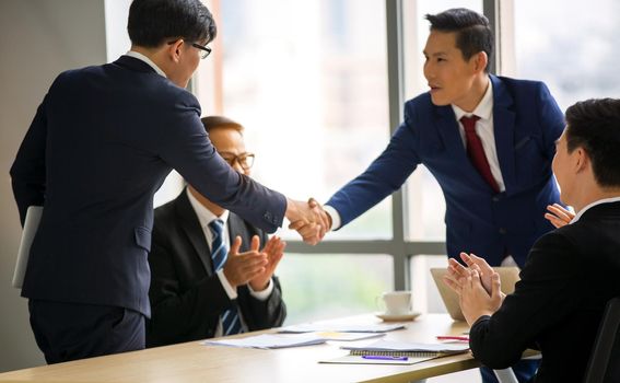 Business people shaking hands in the modern office finishing successful meeting