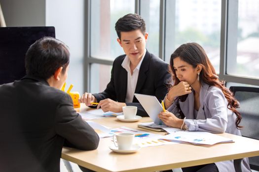 young business team working together at office. Manager pointing at a chart and explaining the analysis about business strategies. Top view shot of business hand shake