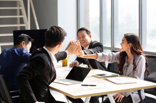 young business team working together at office. Manager pointing at a chart and explaining the analysis about business strategies. Top view shot of business hand shake