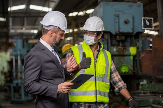 Male Industrial Engineers Talk with Factory Worker . They Work at the Heavy Industry Manufacturing Facility.