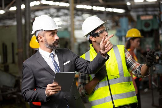 Male Industrial Engineers Talk with Factory Worker . They Work at the Heavy Industry Manufacturing Facility.