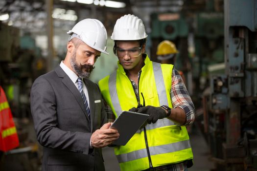 Male Industrial Engineers Talk with Factory Worker . They Work at the Heavy Industry Manufacturing Facility.