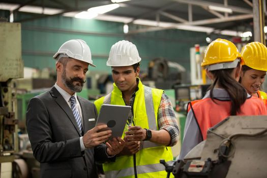 Male Industrial Engineers Talk with Factory Worker . They Work at the Heavy Industry Manufacturing Facility.