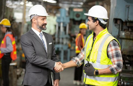 Male Industrial Engineers Talk with Factory Worker . They Work at the Heavy Industry Manufacturing Facility.