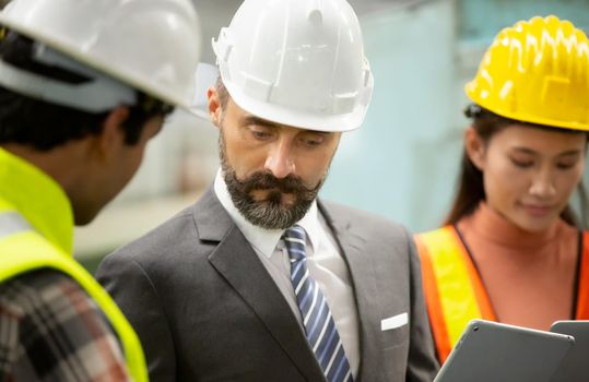 Male Industrial Engineers Talk with Factory Worker . They Work at the Heavy Industry Manufacturing Facility.