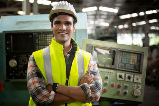 Engineer standing with confident against machine environment in factory