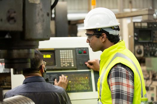 Engineers operating a cnc machine in factory