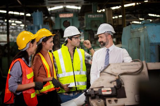 Male Industrial Engineers Talk with Factory Worker . They Work at the Heavy Industry Manufacturing Facility.