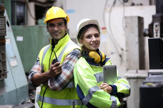 Men and female workers in factory operating machine in workshop floor.