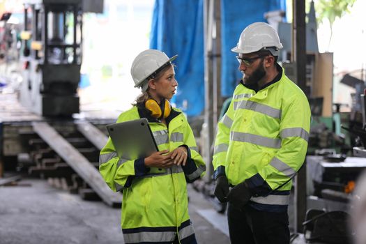 Men and female workers in factory operating machine in workshop floor.