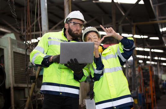 Men and female workers in factory operating machine in workshop floor.	
