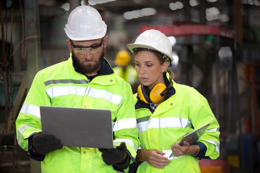 Men and female workers in factory operating machine in workshop floor.