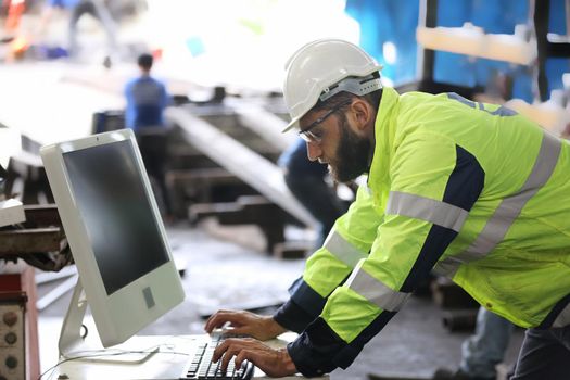 construction worker using laptop, Engineer standing with confident against machine environment in factory