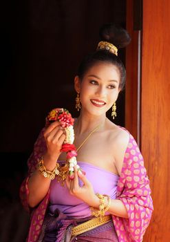 Smiling Woman In Traditional Clothing Looking Away While Standing Against Building