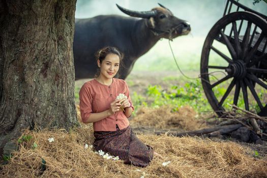 portrait of beautiful Asian woman and buffalo in field at farmland.