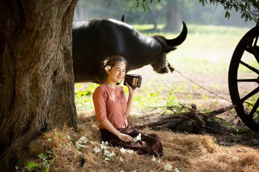 portrait of beautiful Asian woman and buffalo in field at farmland.