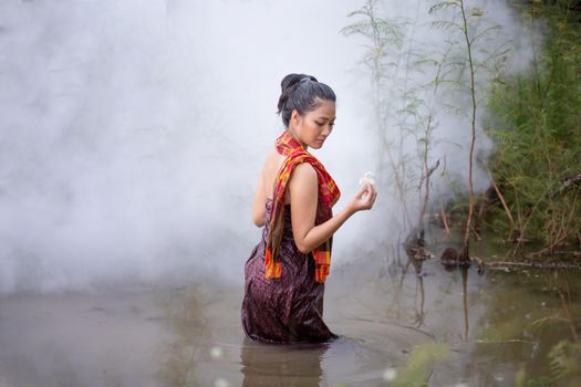 Beautiful Asian women are bathing in the river. Asia girl in Thailand. Asian girl take a shower outdoor from a traditional bamboo chute,countryside Thailand.