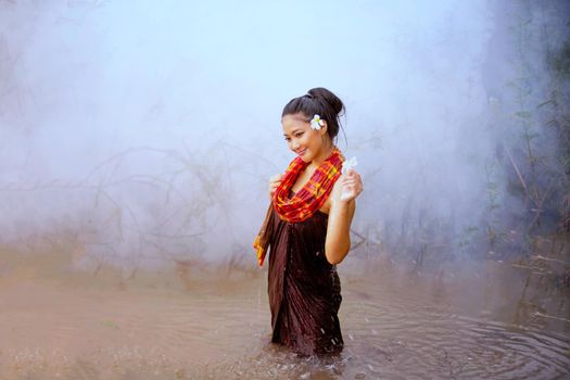 Beautiful Asian women are bathing in the river. Asia girl in Thailand. Asian girl take a shower outdoor from a traditional bamboo chute,countryside Thailand.