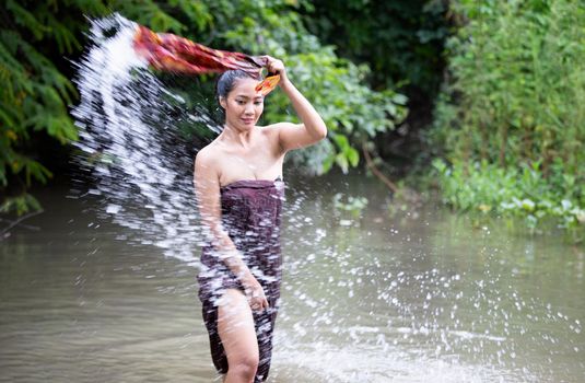 Beautiful Asian women are bathing in the river. Asia girl in Thailand. Asian girl take a shower outdoor from a traditional bamboo chute,countryside Thailand.