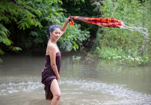 Beautiful Asian women are bathing in the river. Asia girl in Thailand. Asian girl take a shower outdoor from a traditional bamboo chute,countryside Thailand.