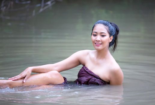 Beautiful Asian women are bathing in the river. Asia girl in Thailand. Asian girl take a shower outdoor from a traditional bamboo chute,countryside Thailand.