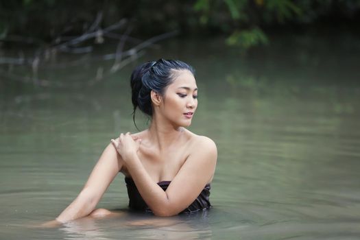 Beautiful Asian women are bathing in the river. Asia girl in Thailand. Asian girl take a shower outdoor from a traditional bamboo chute,countryside Thailand.