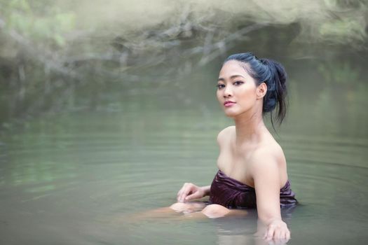 Beautiful Asian women are bathing in the river. Asia girl in Thailand. Asian girl take a shower outdoor from a traditional bamboo chute,countryside Thailand.