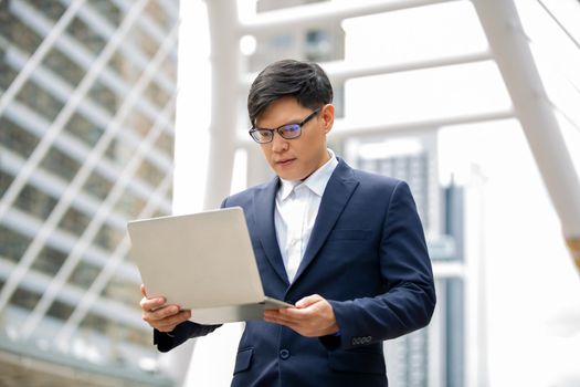 Business person using laptop at outside office.