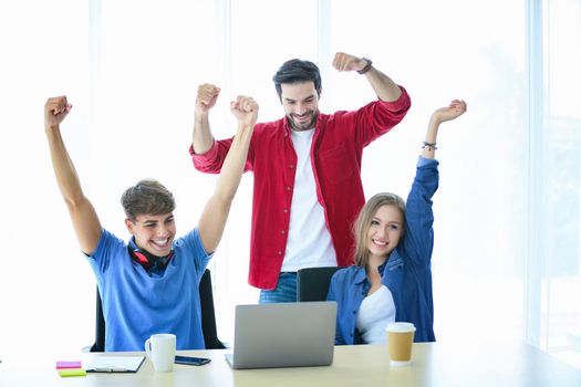 Business people working in office on desktop computer, Group of happy business people in smart casual wear looking at the laptop and gesturing. Achieving success.