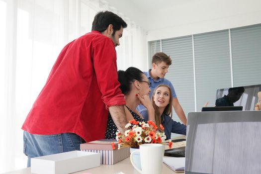 Business people working in office on desktop computer, Group of happy business people in smart casual wear looking at the laptop and gesturing. Achieving success.