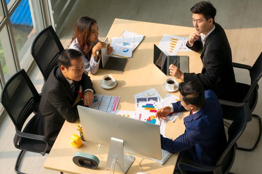 young business team working together at office. Manager pointing at a chart and explaining the analysis about business strategies. Top view shot of business hand shake