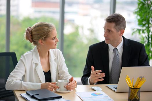 young business team working together at office. Manager pointing at a chart and explaining the analysis about business strategies. Top view shot of business hand shake