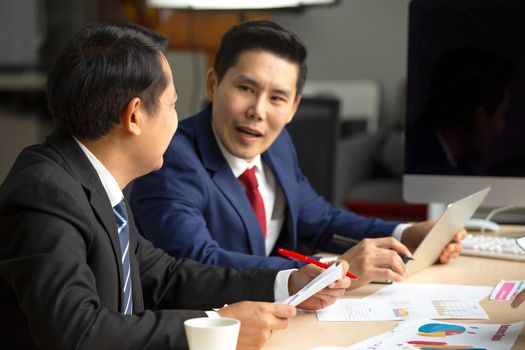 young business team working together at office. Manager pointing at a chart and explaining the analysis about business strategies. Top view shot of business hand shake