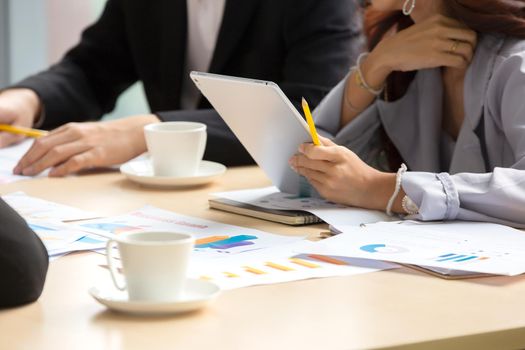 young business team working together at office. Manager pointing at a chart and explaining the analysis about business strategies. Top view shot of business hand shake