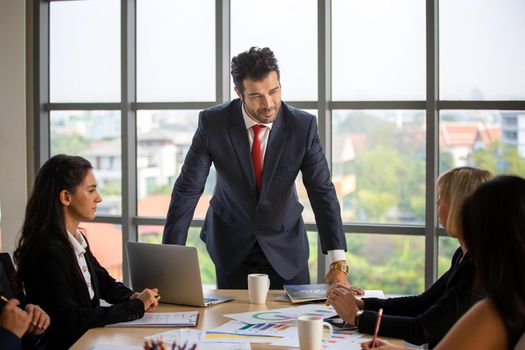 young business team working together at office. Manager pointing at a chart and explaining the analysis about business strategies. Top view shot of business hand shake