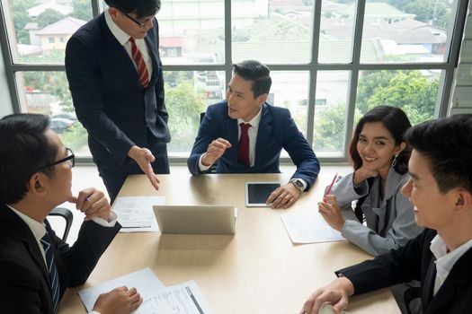 young business team working together at office. Manager pointing at a chart and explaining the analysis about business strategies. Top view shot of business hand shake