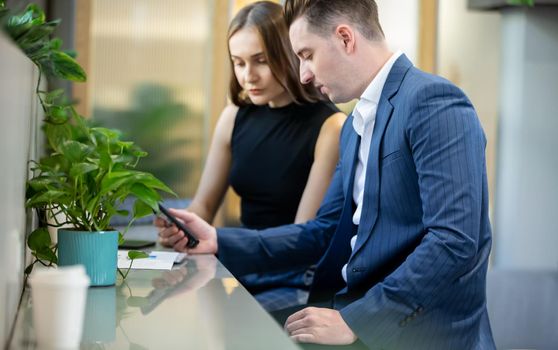 Two business people sitting at cafe working on new project using laptop. Young businesswoman taking notes and businessman working on laptop computer.