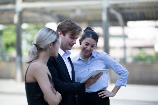 Businessman and women sitting on step outdoor looking on laptop against building