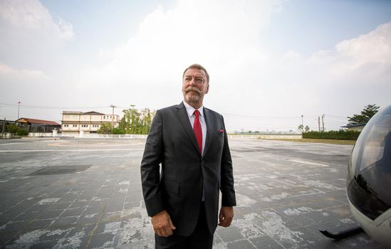 confident business people standing against his private helicopter at landing airport. Professional career success concept