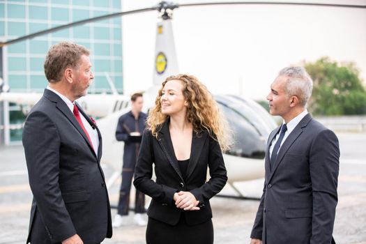 confident business people standing against his private helicopter at landing airport. Professional career success concept	