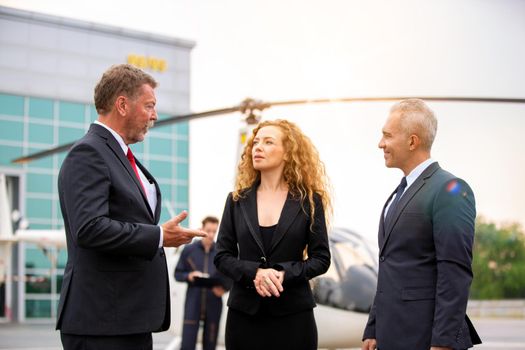 confident business people standing against his private helicopter at landing airport. Professional career success concept	