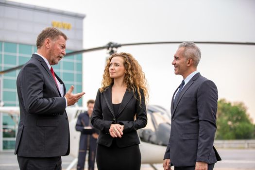 confident business people standing against his private helicopter at landing airport. Professional career success concept	