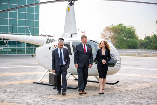 confident business people standing against his private helicopter at landing airport. Professional career success concept	