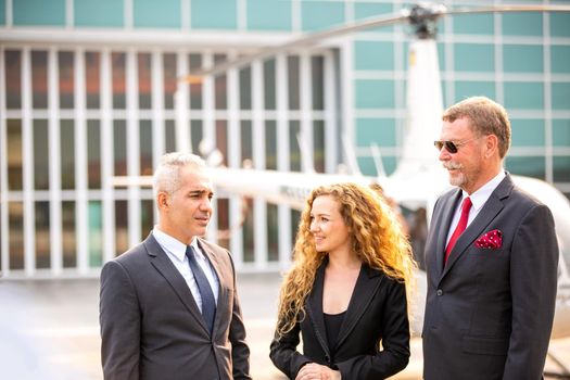 confident business people standing against his private helicopter at landing airport. Professional career success concept	