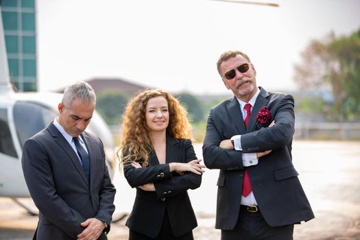 confident business people standing against his private helicopter at landing airport. Professional career success concept	