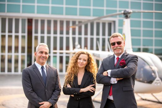 confident business people standing against his private helicopter at landing airport. Professional career success concept	