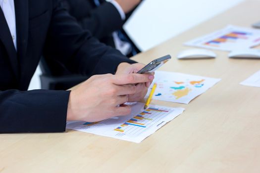 young business team working together at office. Manager pointing at a chart and explaining the analysis about business strategies. Top view shot of business hand shake